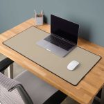 Desk mat mockup on wooden table with laptop and mouse, blank template ready for custom submission design.