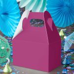 Magenta gable favor box surrounded by confetti, umbrellas, and party décor in bold, festive colors.