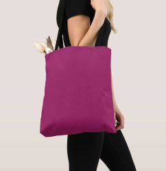 Magenta fabric tote bag with black straps filled with white tulips against a black‐clad backdrop.